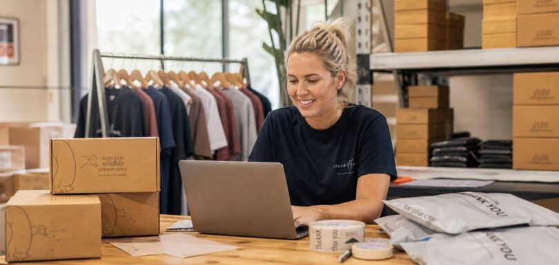Australian ecommerce business owner reviewing online orders in a warehouse packing area