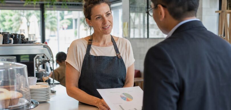 Gold Coast cafe owner reviewing a website performance report with a digital strategist at her Broadbeach shopfront counter