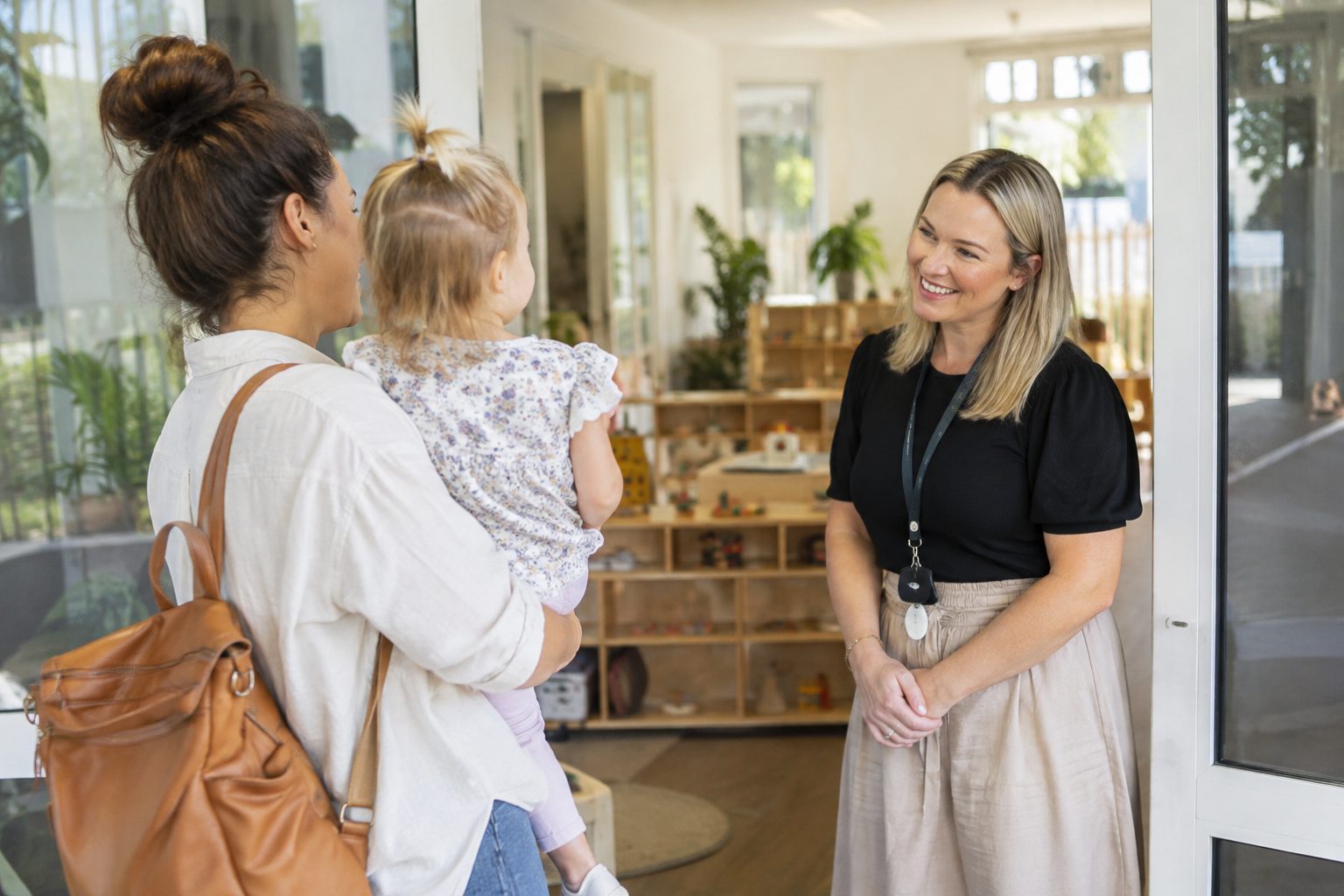 Childcare centre director welcoming a parent and toddler at an early learning centre entrance