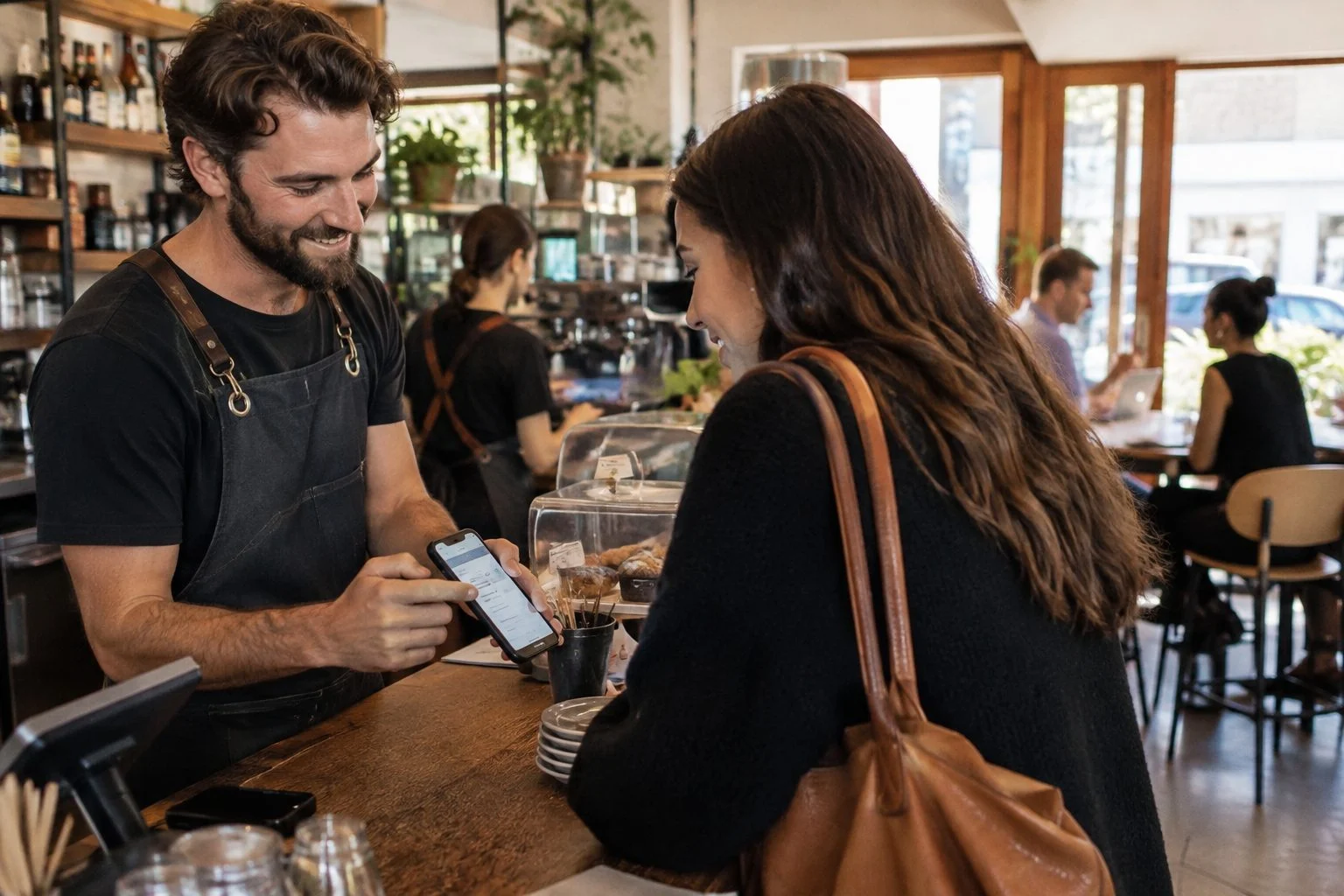 Perth cafe owner showing a customer the menu on a smartphone at the counter
