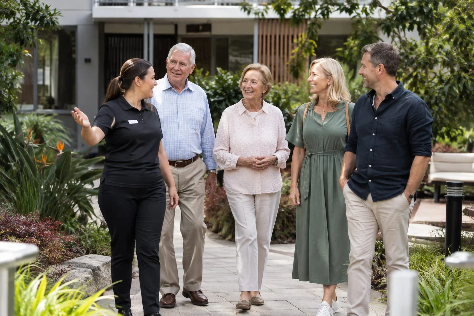 Family with grandparents touring an aged care courtyard garden in Robina with a staff member